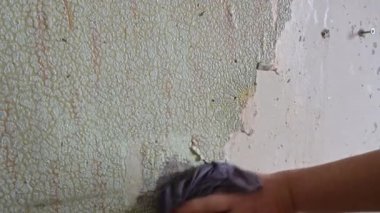Duvardan eski duvar kağıtlarını spatula ve doğaçlama araçlarla kazımak, kendi başına bir apartman dairesini onarmak.