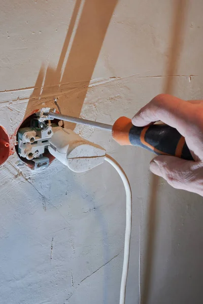 Dangerous connection of an electrical plug to a new socket without a decorative cover installed on a freshly plastered wall. — Stock Photo, Image