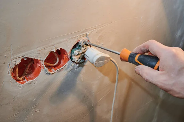 Einbau einer neuen Steckdose in eine frisch verputzte Wand mit Steckverbindung, orangefarbener Schraubenzieher — Stockfoto