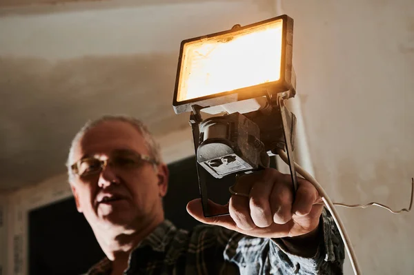 İnşaat alanındaki bir adam, çalıştığı yeri aydınlatmak için kullandığı feneri gösteriyor. — Stok fotoğraf