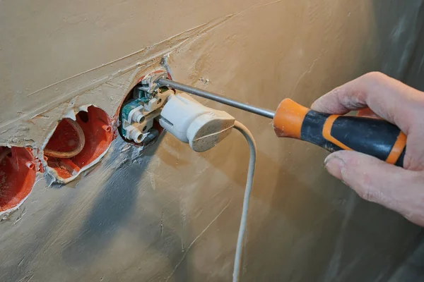 Einbau einer neuen Steckdose in eine frisch verputzte Wand mit Steckverbindung, orangefarbener Schraubenzieher — Stockfoto