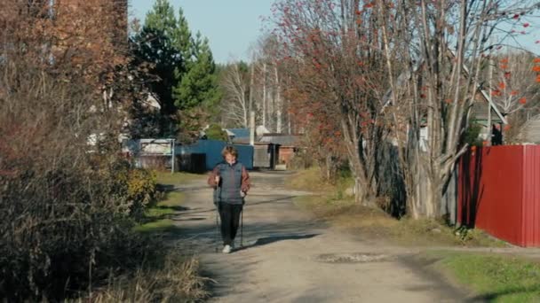Mulher andando com paus escandinavos — Vídeo de Stock