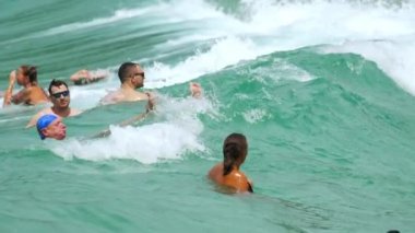 Tatilciler Nai Harn Sahili, Phuket Tayland 'da dalgaların tadını çıkarıyorlar.