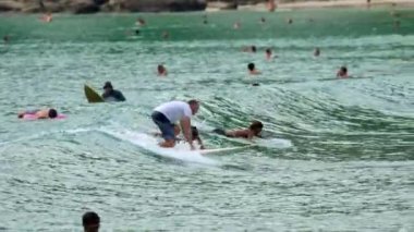 Sörfçüler Nai Harn Sahili, Phuket Tayland 'da dalgaların tadını çıkarırlar.