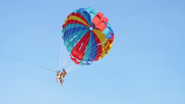 Les touristes descendent sur un parachute coloré — Video