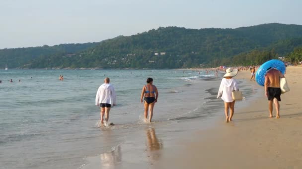 Tourists walk along the seashore — Stockvideo