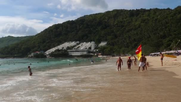 Touristen spazieren an einem heißen Tag am Strand entlang — Stockvideo