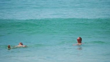 Yüzen insanlar dalgayı yakalar.