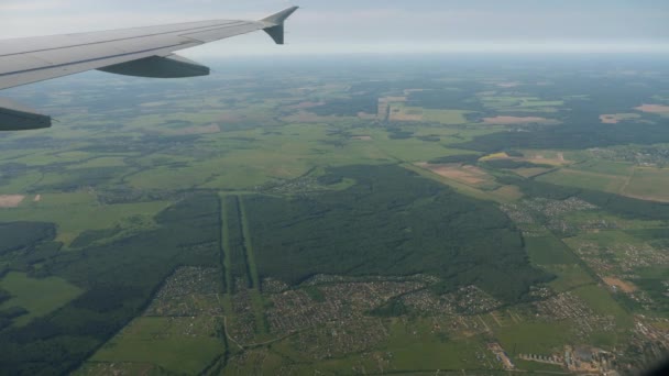 Näkymä lentokoneen ikkunasta vihreisiin metsiin ja pelloille — kuvapankkivideo