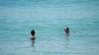 İnsanlar gök mavisi denizde yüzer.