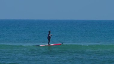 Mavi denizdeki SUP panosundaki kadın.