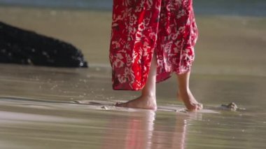 Sahilde kırmızı elbiseli bir kadın.