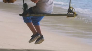 Okyanusun kıyısında salıncakta sallanan bir adam.