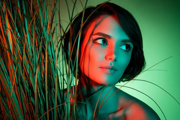Photo de touriste dame aux cheveux courts regarder espace vide posant dans l'herbe haute isolé vert néon fond de couleur claire — Photo