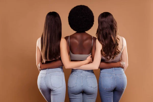 Foto de encantador amistoso tres novias usan tops de las cosechas abrazándose de pie fondo de color beige aislado —  Fotos de Stock