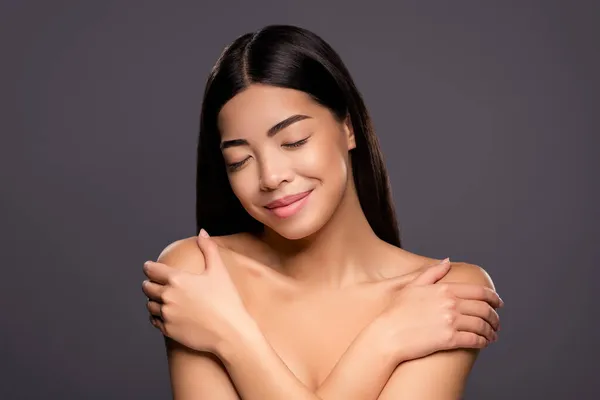 Şirin, pozitif Çinli kadın ellerinin fotoğrafı. Omuzları kapalı, gözleri açık. Yumuşak tenli, izole, gri arka plan. — Stok fotoğraf