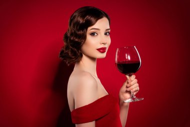 Yeni yıl kutlamalarında kırmızı arka planda izole edilmiş bir partide içkili genç bayanın hassas profilli fotoğrafı.