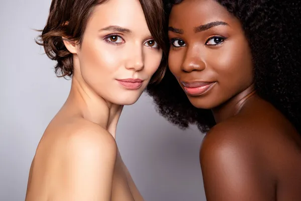 Portret van twee naakte vrouwen die een zuivere gladde, heldere, perfecte huidskleur op een grijze pastelachtergrond binden — Stockfoto