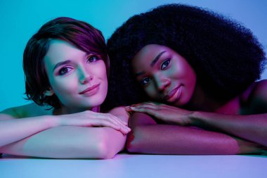 Neon ışıklı arka planda izole edilmiş iki sevimli ve mutlu kadının portresi.