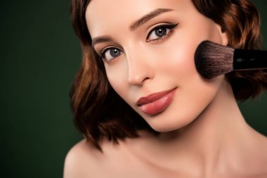 Gülümseyen çarpıcı kızın yakın plan portresi yeşil arka planda izole edilmiş yanaklara temel kalemi uyguluyor.