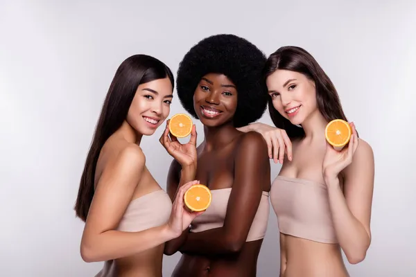 Photo trois jeune femme séduisante heureux sourire positif tenir tranches d'orange agrumes isolés sur fond de couleur grise — Photo
