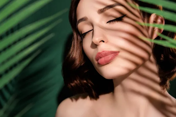 Portret van jonge vrolijke dromerige vrouw met gesloten ogen spa behandeling procedure geïsoleerd op groene bloemen achtergrond — Stockfoto