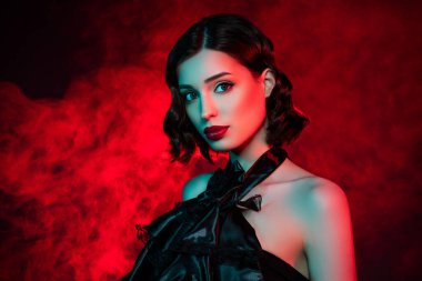 Çekici ve güzel bir kadının fotoğrafı kırmızı ruj sürerken Ekim parti stili giyiniyor. Vampirler neon sisli arka planda izole edilmiş.