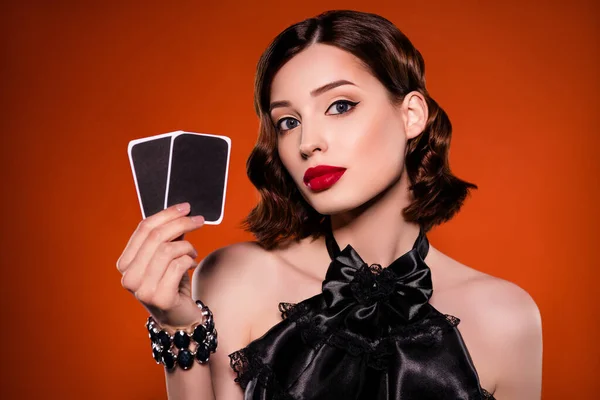 Foto de atractiva mujer joven impresionante cogida de la mano cartas suerte juego aislado sobre fondo de color naranja oscuro —  Fotos de Stock