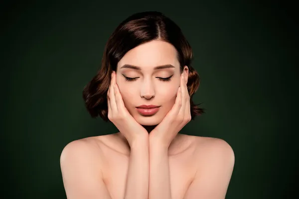 Фото спокойной мирной закрытые глаза женщина прикосновения щеки нанести увлажняющий крем тонер изолированы на зеленый цвет фона — стоковое фото