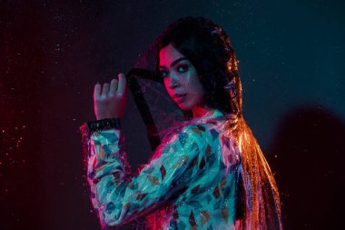 Profil tarafı fotoğrafı. Kapüşonlu ceket giyen güzel bir kadın. Muson yağmurlarını koruyor.