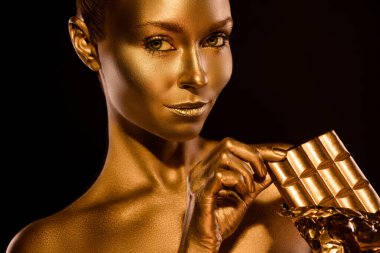 Kapalı tenli kadın portresi. Çikolata yiyin. Nefis bir beklenti, izole edilmiş koyu renk arka plan.