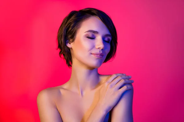 Photo of cute hairdo young lady closed eyes hug herself without clothes isolated on vibrant neon red color background — Stock Fotó