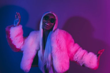 Genç kızın çekici resmi geceyi kulüpte pembe renkli arka planda izole edilmiş diğer insanlarla dans ederek geçiriyor..