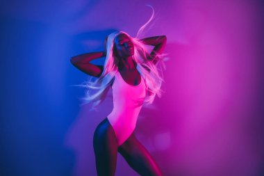 Gece kulübünde poz veren güzel bir kadının güzel fotoğrafı. Pembe floresan arka planda izole edilmiş havada uçuşan saçları hisset..