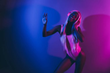 Çekici bir bayanın parti vesilesiyle takıldığı fotoğraf. Mor renkli canlı arka planda izole edilmiş telsiz kulaklıkları dinle..