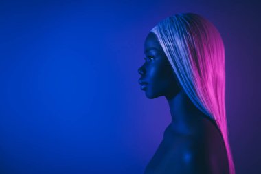 Profil görüntüsü: Çekici, çıplak, düz, uzun, yapay saçlı kadın çok renkli arkaplanda boş görünüyor..