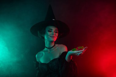 Photo of lady in fiction personage dress halloween theme event hold marmalade jelly isolated on mystic dark background.