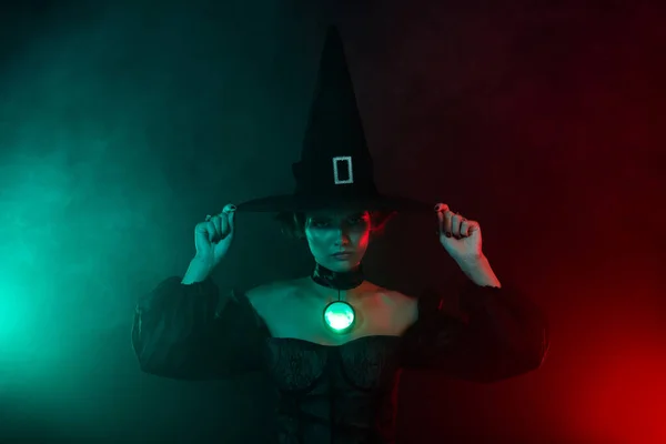 邪悪な女性の写真は神秘的な煙の色の背景に隔離された魔法の工芸品の宝石ペンダントマスケードヘッドウェアを行う — ストック写真