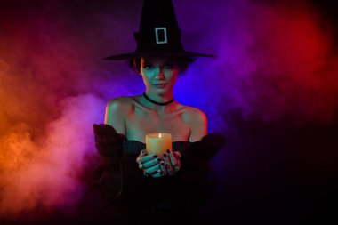 Kadın büyücünün fotoğrafı mum ateşi büyüsü karanlık, gizemli kötü büyü parlak renkli arka planda izole edilmiş..