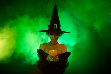 Kötü kalpli kadın büyüsünün fotoğrafı parlak yeşil ışık arka planında izole edilmiş mum alevi kullan.