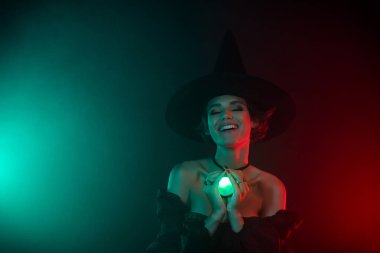 Lanetli kadın büyücü ayin yaparken çekilmiş bir fotoğraf. Mavi kırmızı sisli arka planda izole edilmiş değerli taş madalyon kullanılmış..