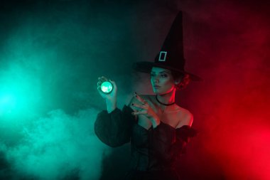 Lanetli kadın büyücünün, parlak renk efektleriyle izole edilmiş dolunay ormanında büyü yaptığı fotoğraf..