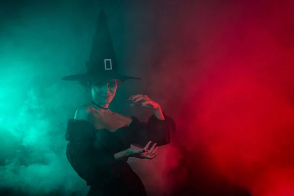 写真のウォーロック女性の宣伝テーマハロウィンカーニバルは神秘的な霧の色の背景に隔離された呪文の魔術をキャストします — ストック写真