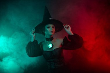 Kötü kalpli kadın büyücü profesörün mistik sisli arka planda temalı karnaval elbisesi şapkasına dokunuşunun fotoğrafı..