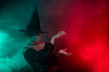 Büyücü kadın karakterin fotoğrafı sihirbaz büyüsü yapıyor. Gizemli dumanlı arka planda izole uzay büyüsü yapıyor..