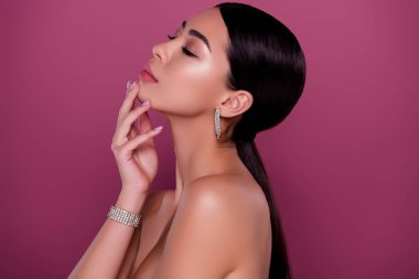 Profil tarafı fotoğrafı, muhteşem bir bayanın spa tesisinde vücudunun kabuğunu soyarken, çenesine dokunurken, izole edilmiş pembe arka plan..