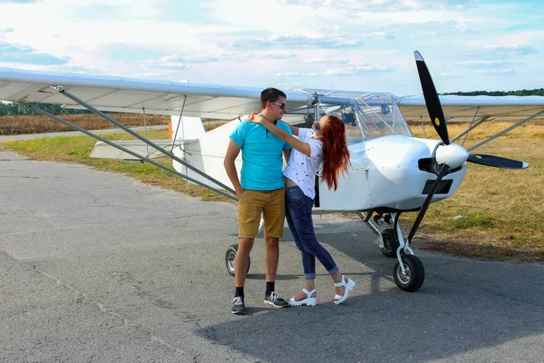 Girl and guy in the background a small plane.