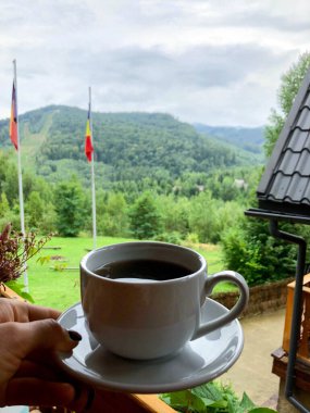 Yazın dağların arka planına yakın beyaz kahve fincanı.