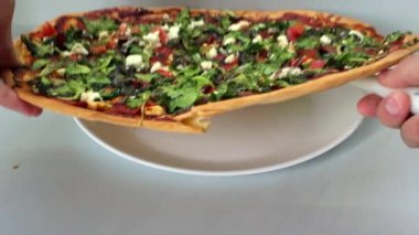 Şefin elleri pizzayı beyaz bir tabağa koyuyor. Fast food konsepti