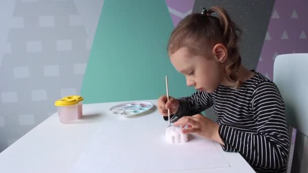 一个3 4岁的欧洲模样的卷曲小女孩坐在书桌前 画了一个河马的石膏雕像 教育概念 家庭业余爱好和有趣的游戏 — 图库视频影像